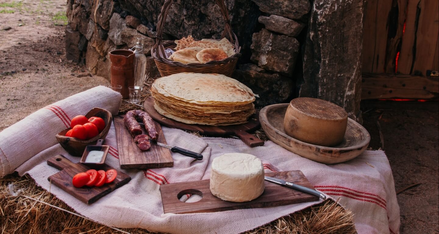 Pane carasau, fresh pecorino and cured meats laid out on handwoven cloth