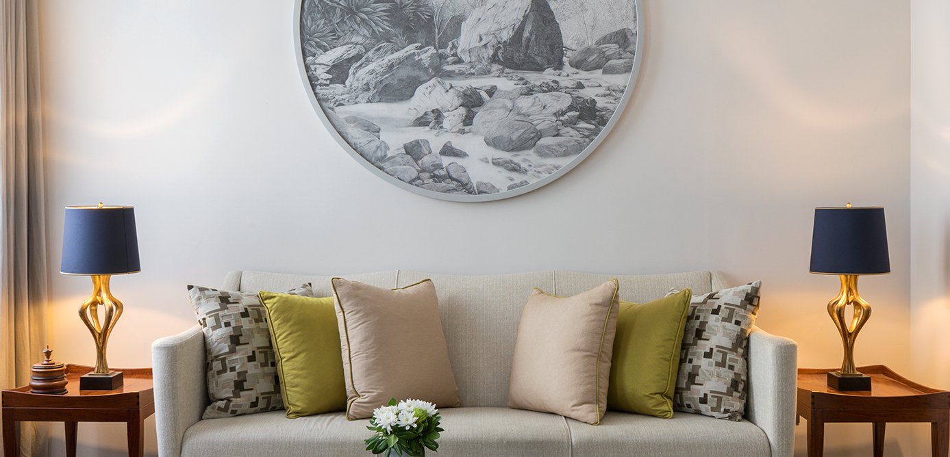 A suite sitting room with a circular contemporary artwork above the sofa