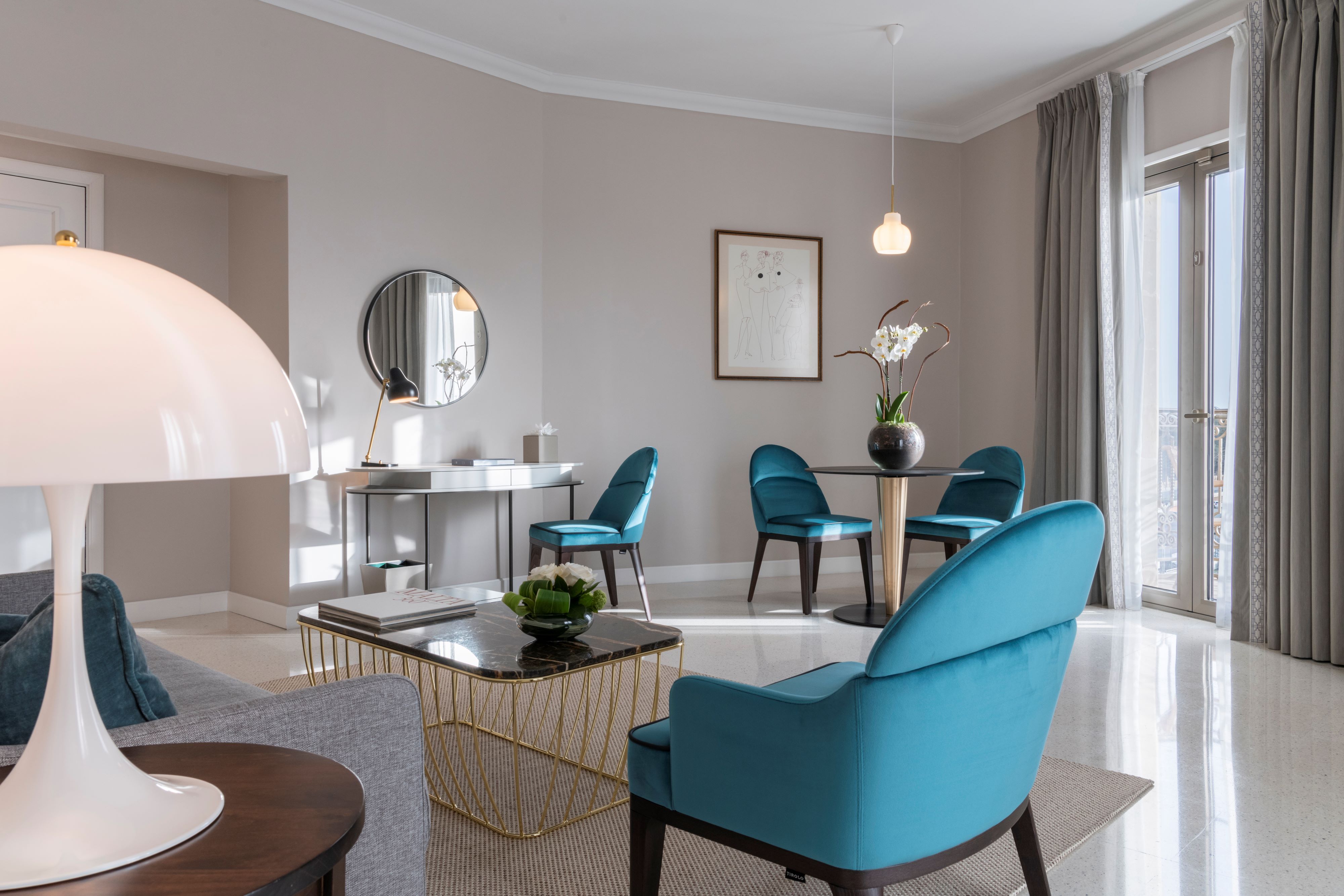 The living room of a Harbour View Suite with teal armchairs and a harbour balcony