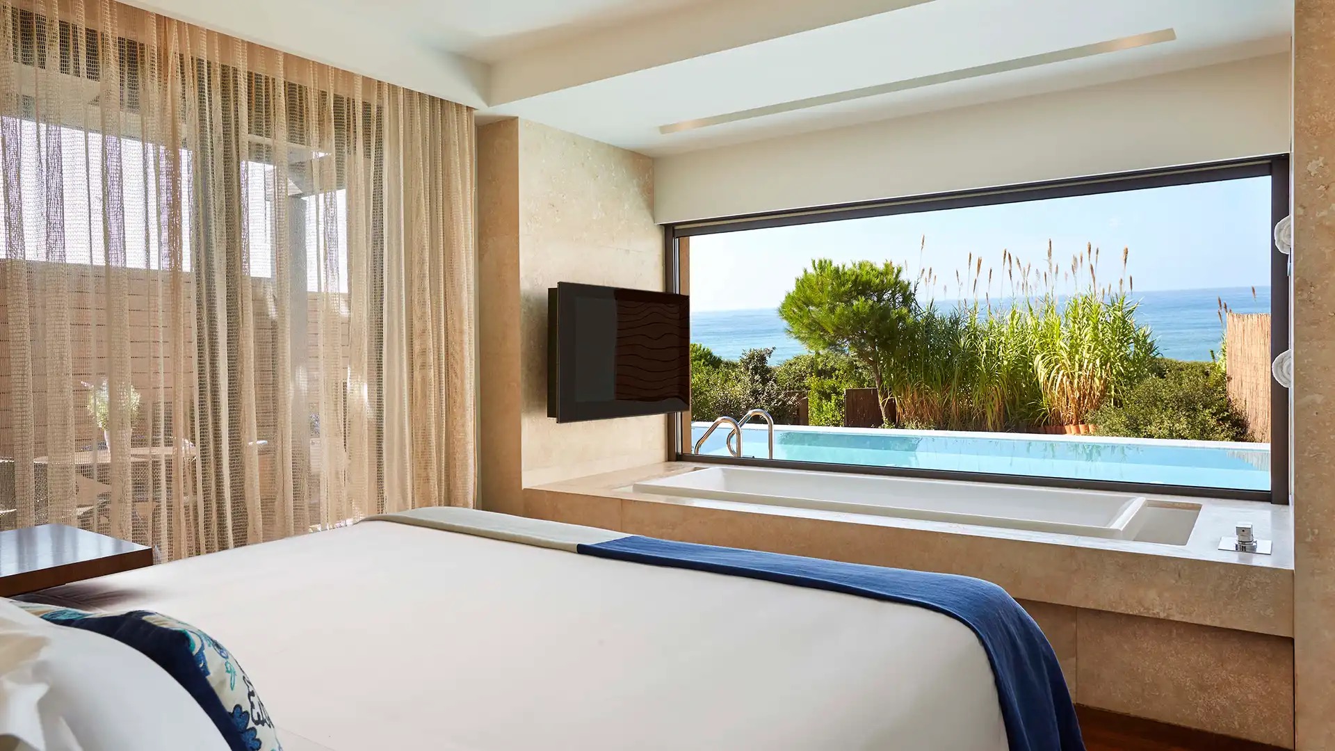 Suite bedroom with a window onto a private pool and the sea