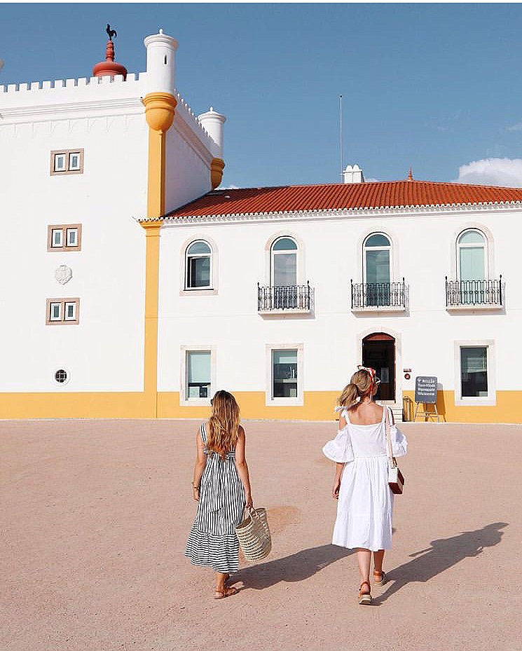 The whitewashed estate buildings and tower of Torre de Palma with guests crossing the courtyard