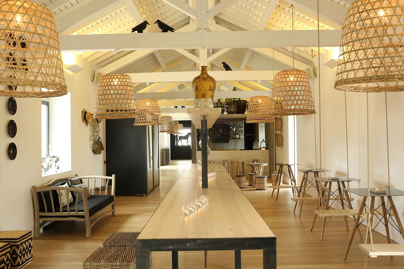 A bright vaulted salon with rattan pendant lights and a bar counter