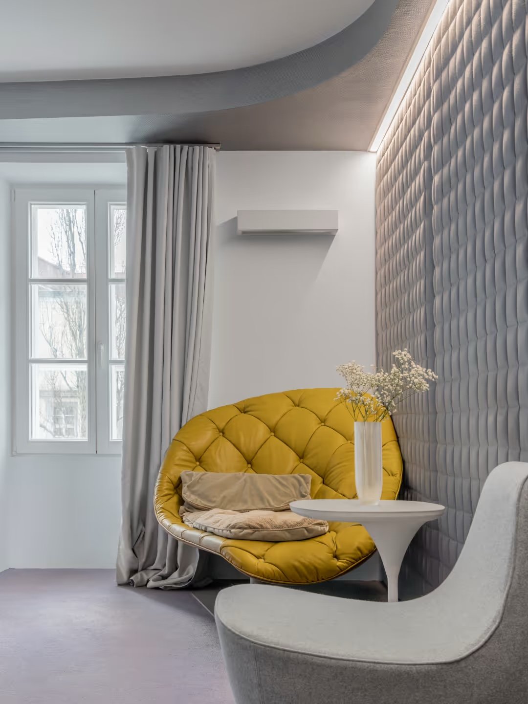 A guest room with a yellow Moroso chair against a textured, three-dimensional wall