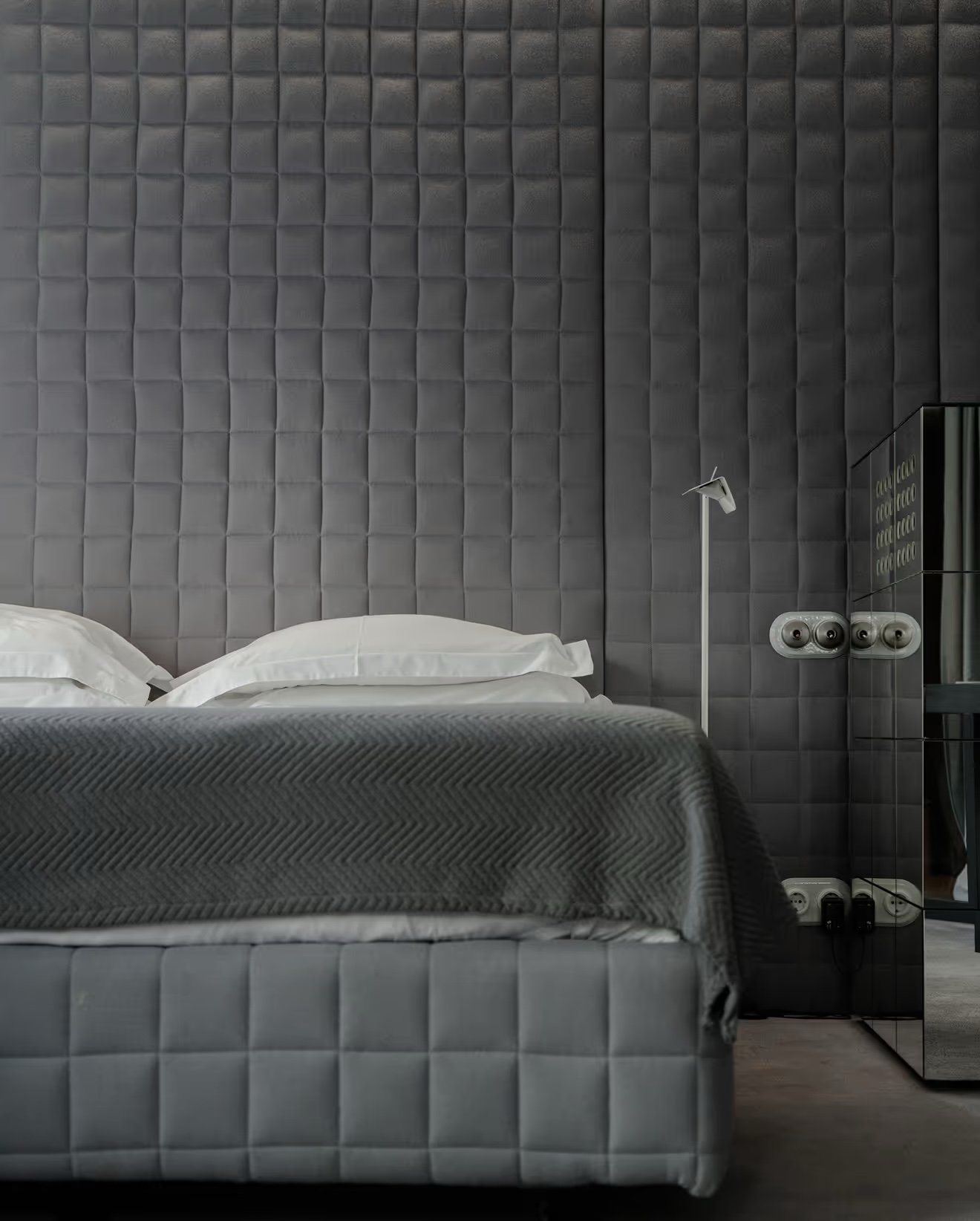 A Vander room with a quilted grey headboard and white linen