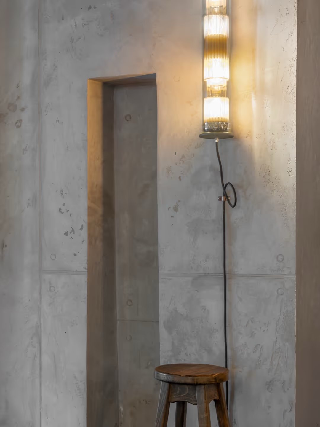 A quiet corner of bare plaster under a reeded-glass light