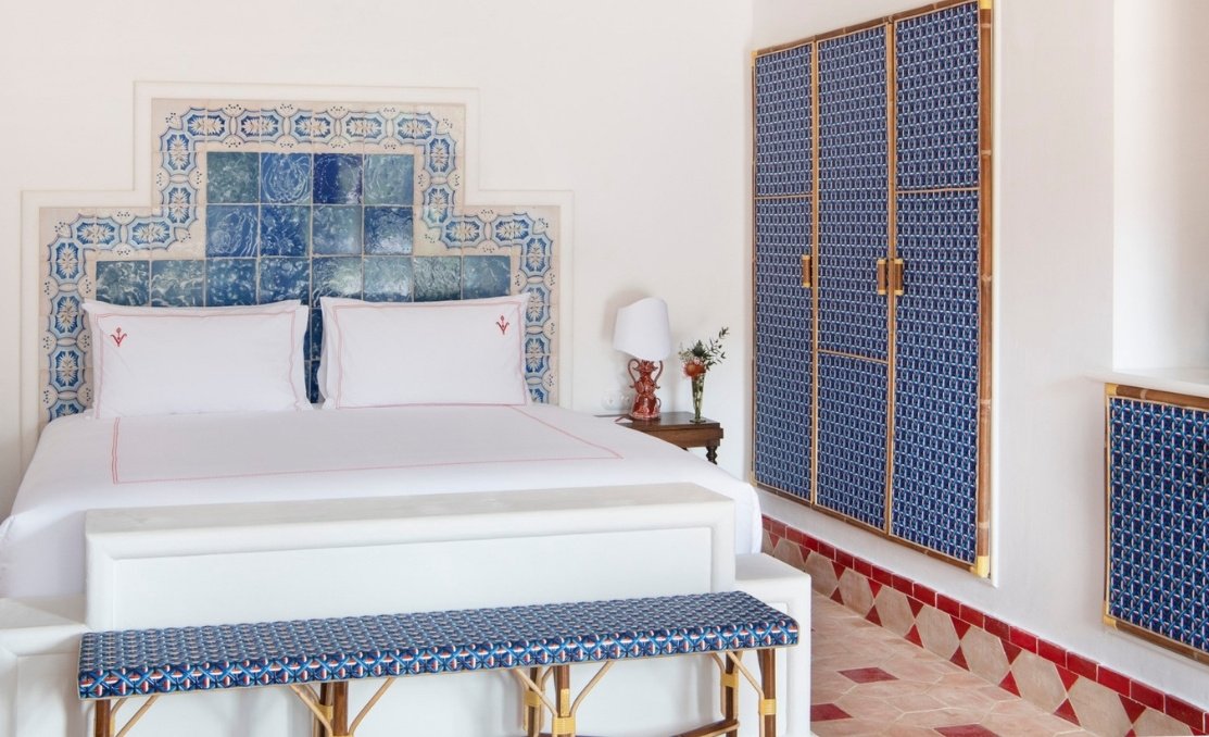 A guest room with a headboard of blue-and-white azulejo tiles and a terracotta floor