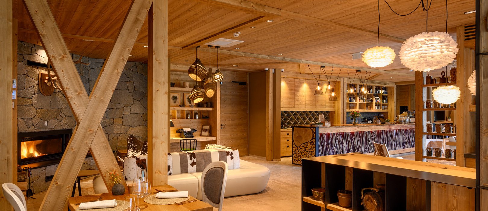 The lounge, with a stone fireplace, timber beams and feather pendant lights