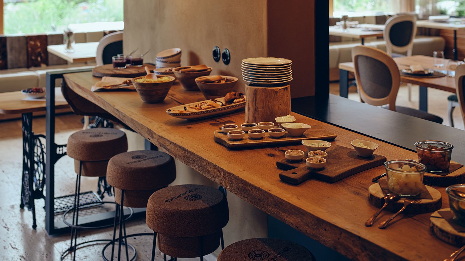 A long wood counter in the restaurant set with local dishes and cork stools