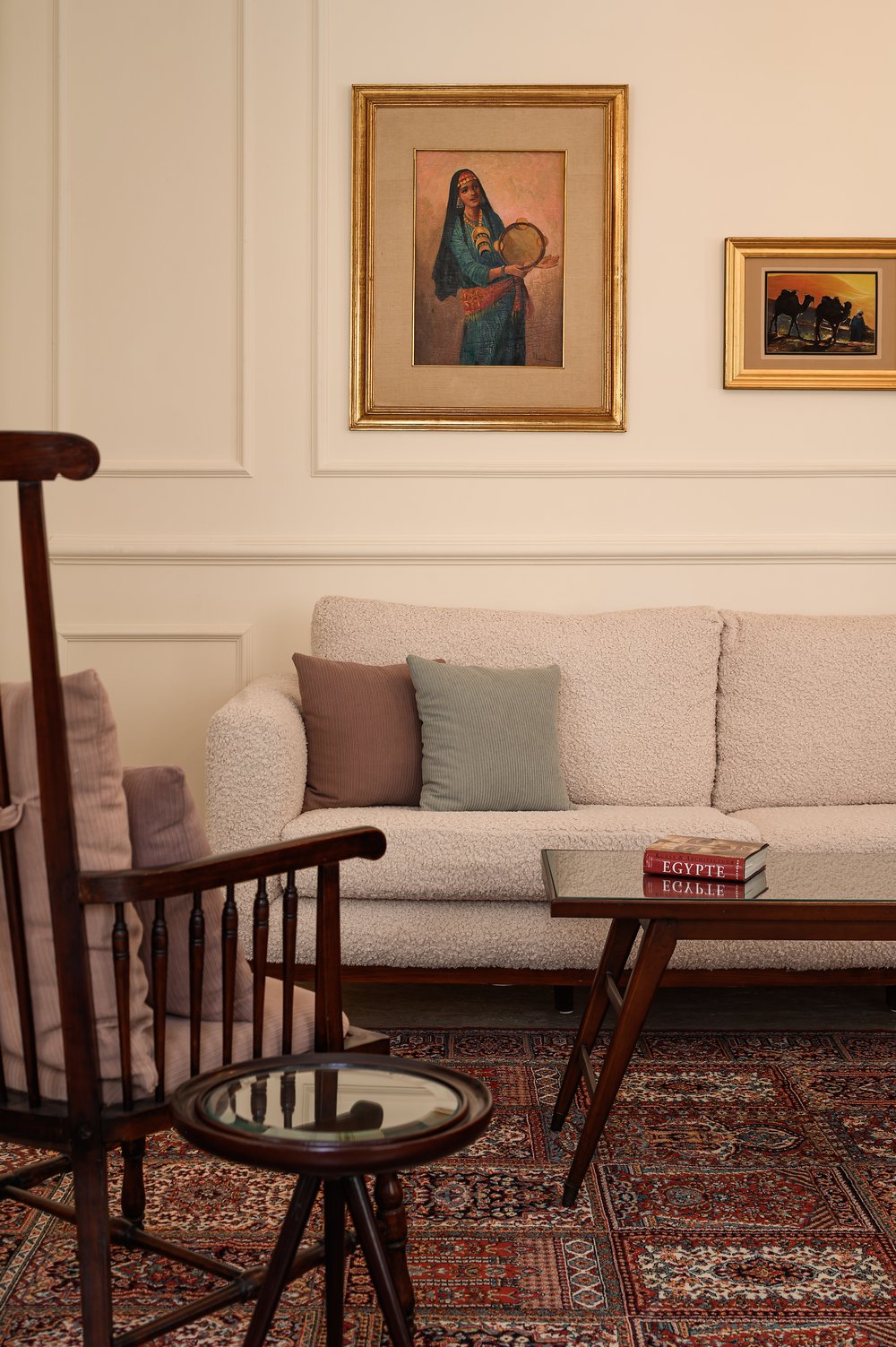 A sitting room with a bouclé sofa below an antique Egyptian painting