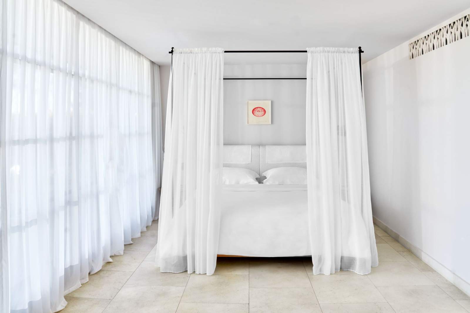 A suite with a canopy bed and a stone floor open to the Provençal light