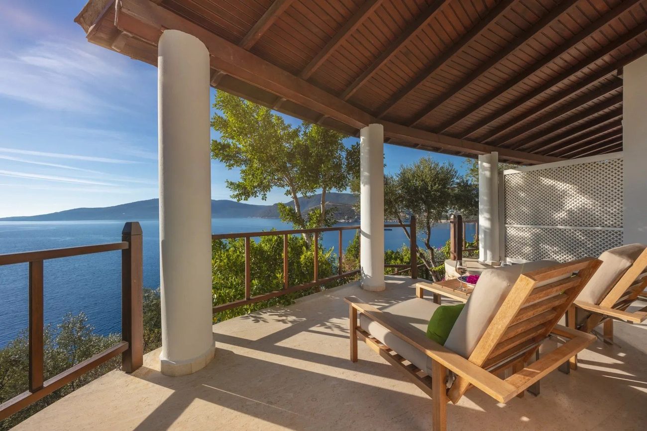 A room's private terrace with columns and a wooden ceiling, open to the sea