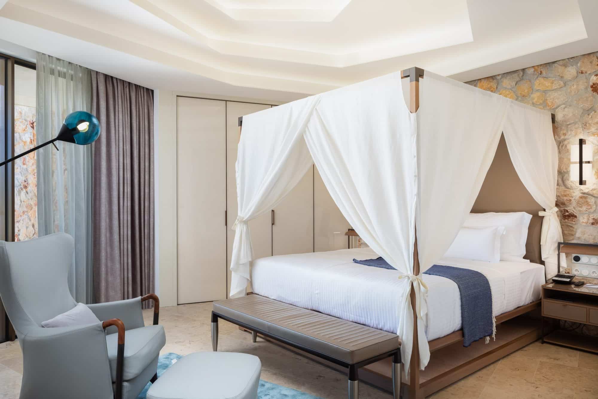 A suite with a four-poster bed set against a bare stone wall