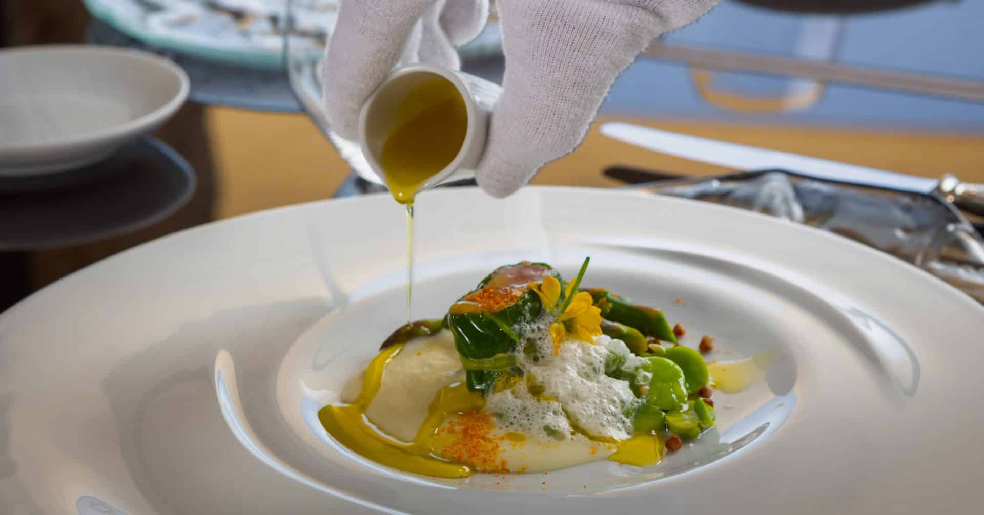 Estate olive oil poured over a plated course at the table