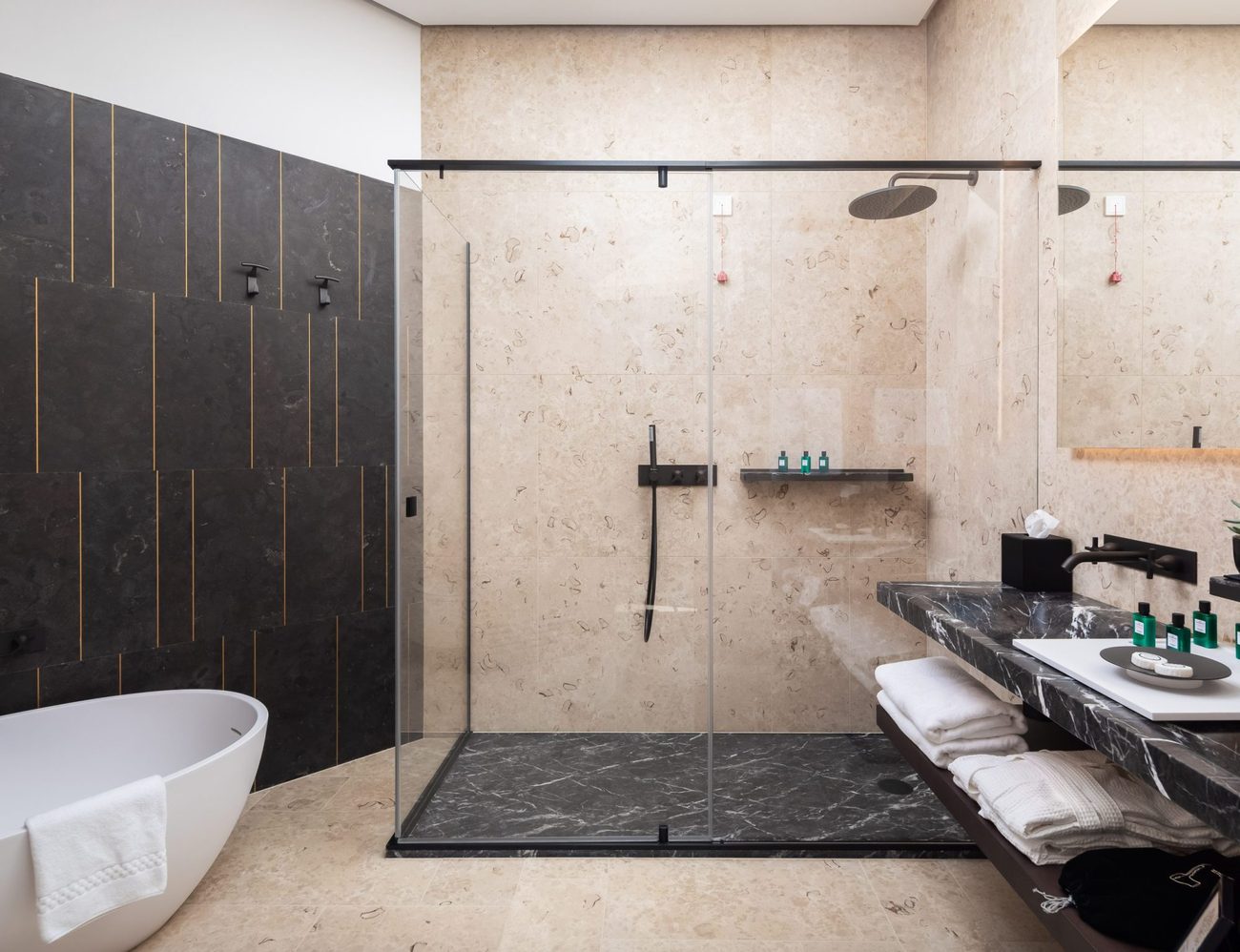 A bathroom lined in pale local stone with a freestanding tub