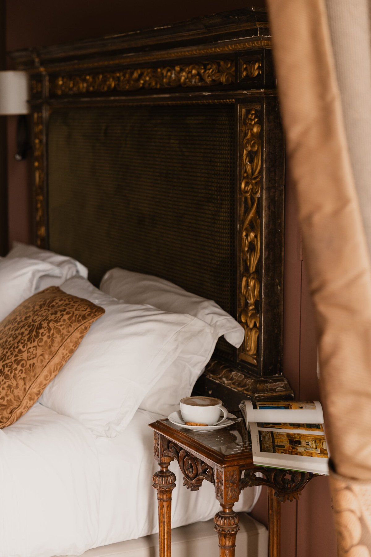 A room dressed with a gilded antique headboard and Parisian fabrics